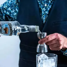Wybierasz jaka wódka na wesele? Zubrówka Biała nalewana do jiggera, przygotowując drinka z lodem.