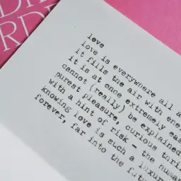 Piękny wiersz o miłości i tęsknocie, z tekstem "love is everywhere" na białej kartce, obok różowej okładki z napisem "AUDRE LORDE".