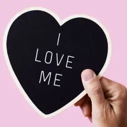 Dłoń trzyma serce z napisem "I LOVE ME". To jak wzruszający wiersz o miłości do samego siebie, który warto pielęgnować.